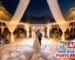 Newlywed couple performing a first dance with low lying fog dancing in the clouds effect under a white high peak wedding tent during sunset