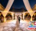 Newlywed couple performing a first dance with low lying fog dancing in the clouds effect under a white high peak wedding tent during sunset