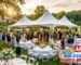 Outdoor wedding reception setup under a white high peak commercial tent in New Jersey featuring guest round tables, patio heaters, a wooden dance floor, and a catering buffet