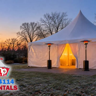 White high peak tent with closed walls glowing at dusk on a New Jersey lawn in late autumn